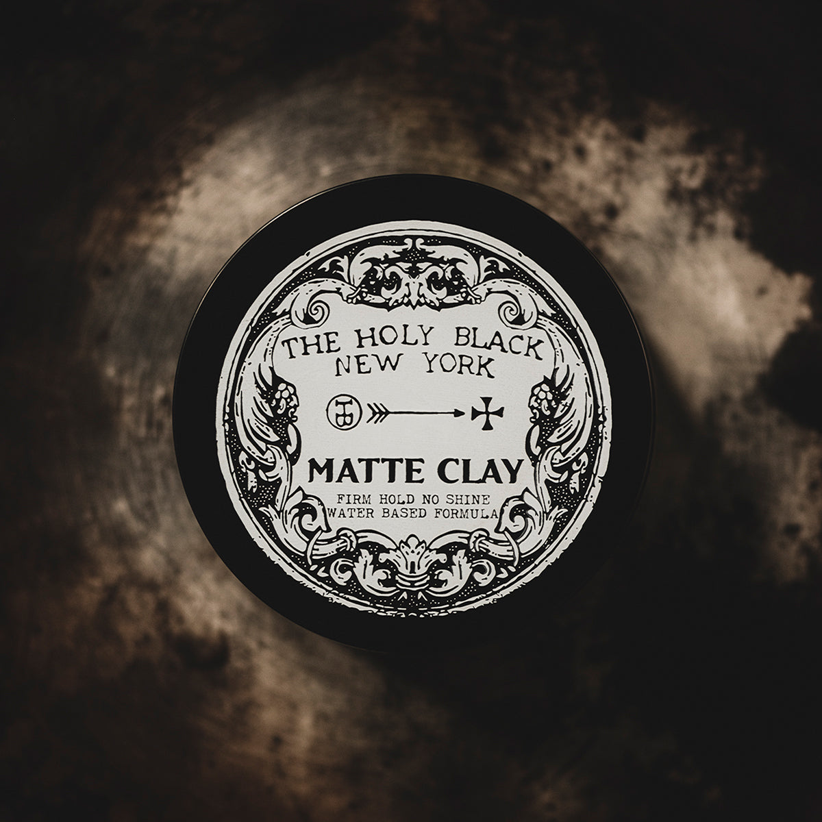 The Holy Black Matte Clay Hair Pomade — matte pomade jar on dark surface