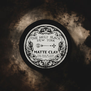The Holy Black Matte Clay Hair Pomade — matte pomade jar on dark surface